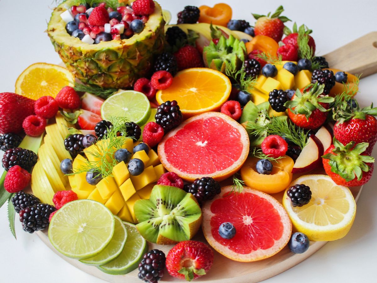 Colorful fresh fruit platter on a round wooden board with pineapple, citrus, and berries