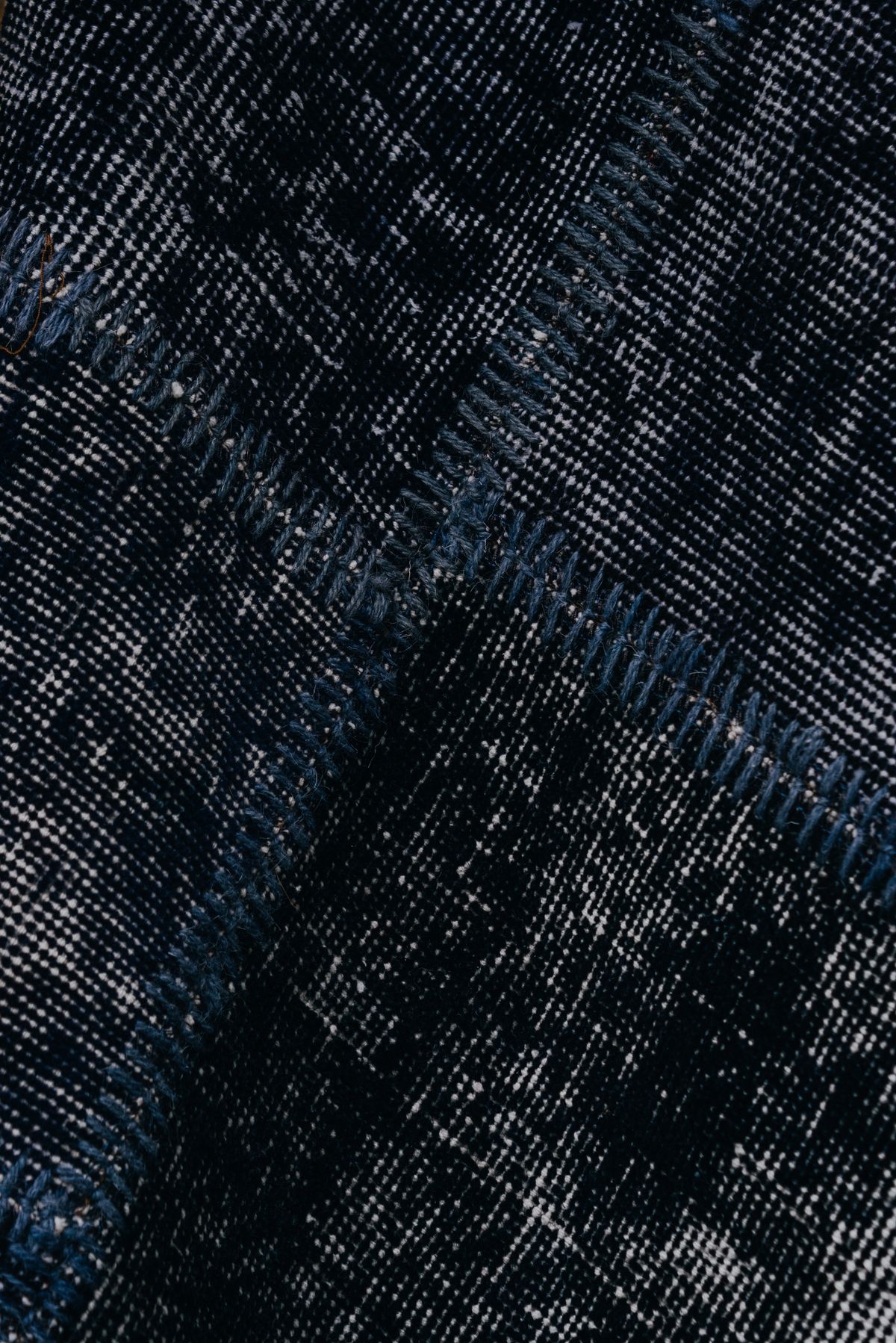 Close-up of dark navy woven fabric panels joined with thick blue whipstitch seams