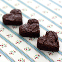 Three heart-shaped dark chocolate brownies with crinkled tops on blue-and-white striped cloth