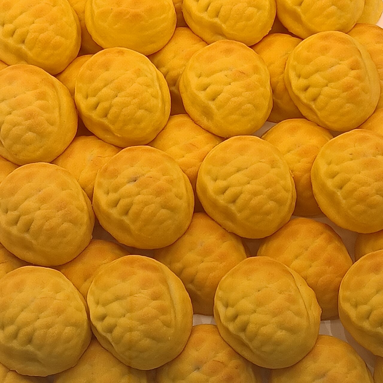 Close pile of round golden-orange cookies with grid-patterned textured tops