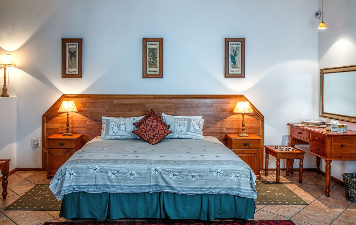 Warmly lit bedroom with a made bed, wooden headboard, and bedside lamps