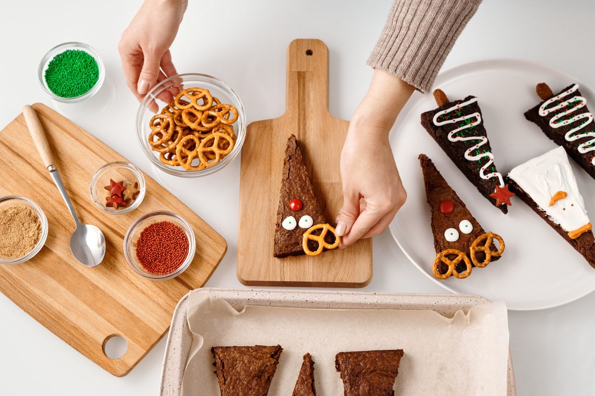 Triangular brownies decorated as reindeer, Christmas trees, and snowmen on a cutting board