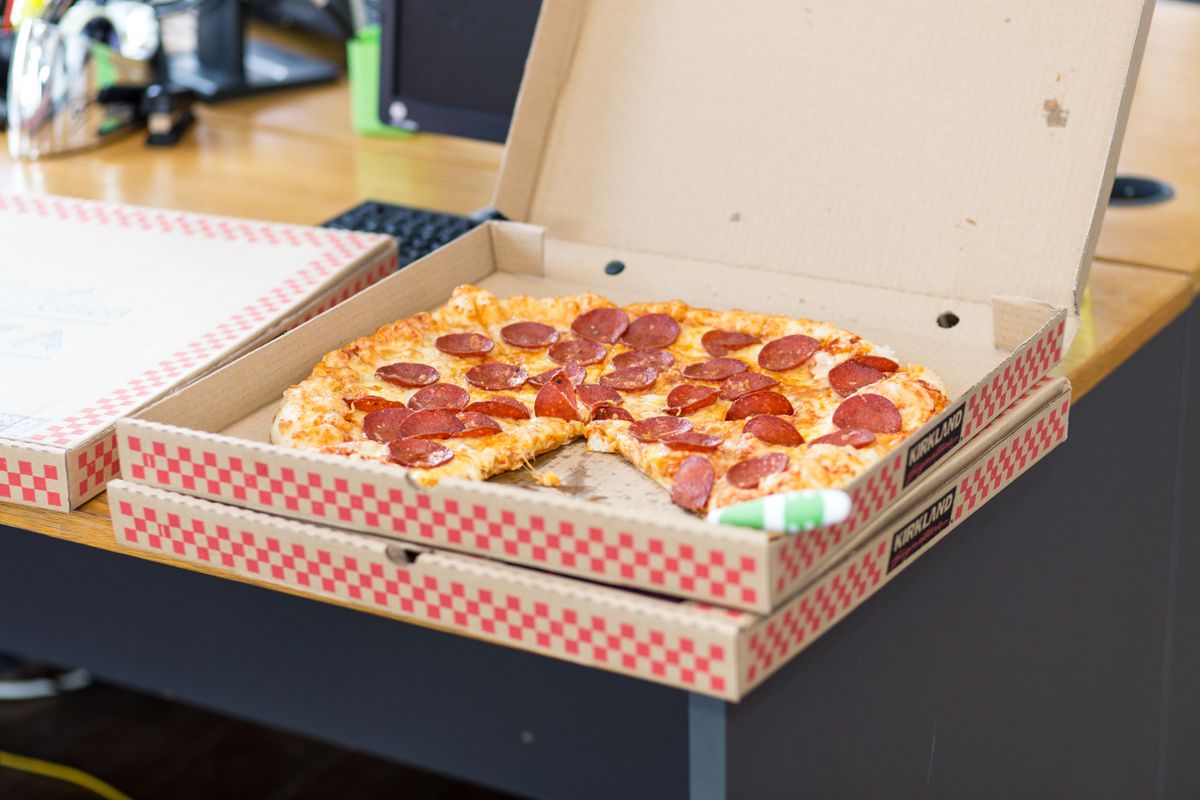 Pepperoni pizza with missing slices in an open Kirkland Signature cardboard box