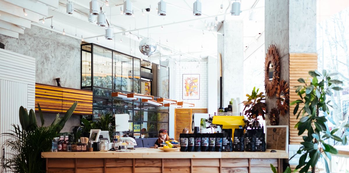Bright cafe interior with wood counter, yellow espresso machine, plants, and hanging disco ball