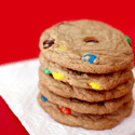 Stack of five thick golden-brown cookies studded with red, blue, yellow, and green candy-coated chocolate pieces