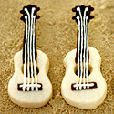 Two ukulele-shaped shortbread cookies with chocolate necks and white icing strings on a sandy background