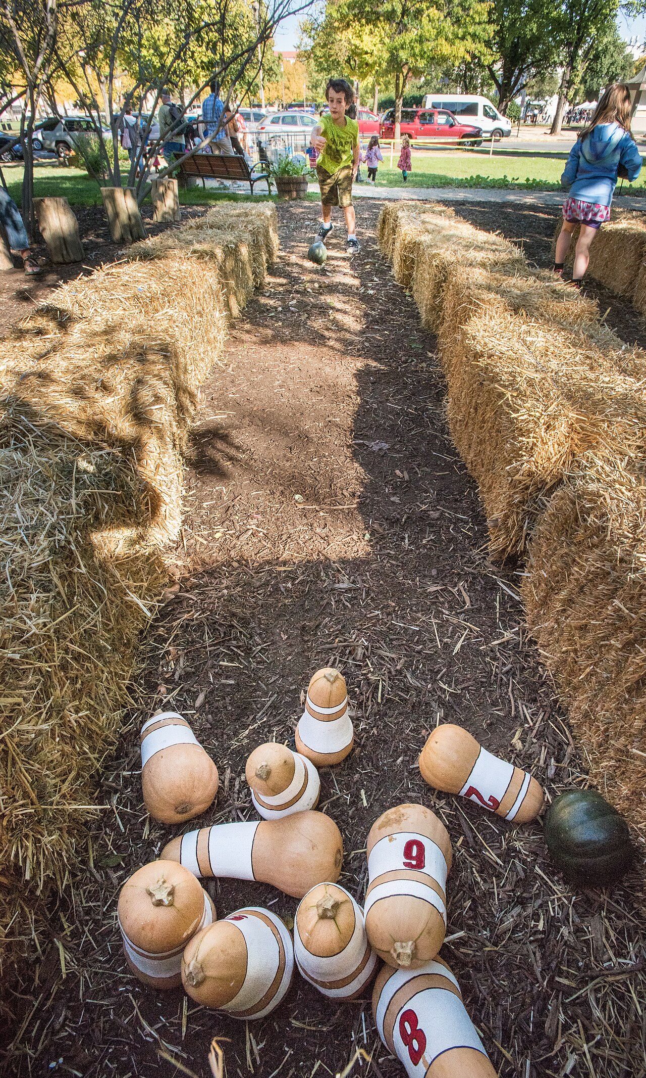 Numbered butternut squashes set as bowling pins on a hay-bale lane outdoors